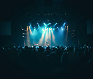 A crowd of people in a dark concert venue with lighted stage